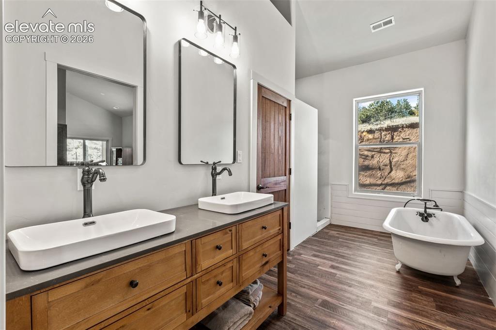 Image 23 of 42: Wood-finish flooring, dual vessel sinks on a wood vanity with a solid count