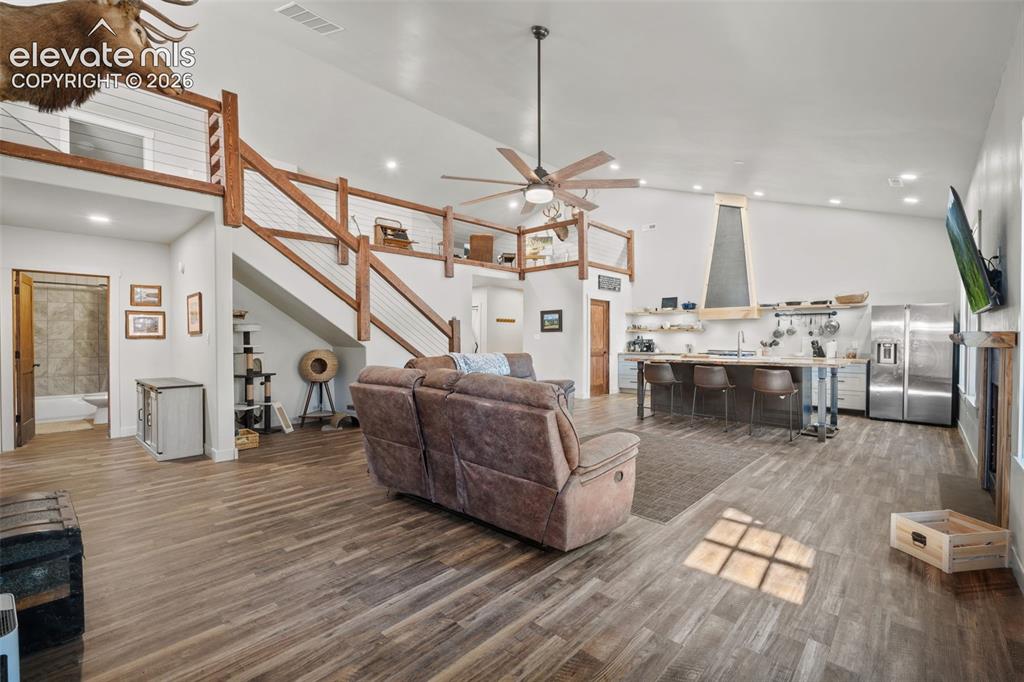 Image 6 of 42: Spacious open-concept living area featuring high vaulted ceilings, wood-fin