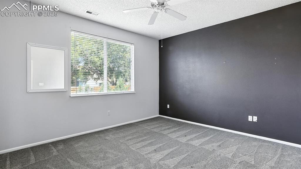 Image 15 of 26: Primary Suite with lighted ceiling fan, neutral carpet, walk in closet, and