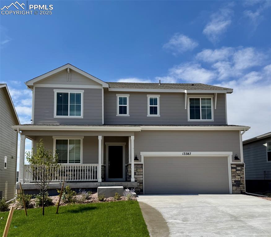 Caption: View of front of home with a porch, an attached garage, concrete driveway, a front yard, and stone s