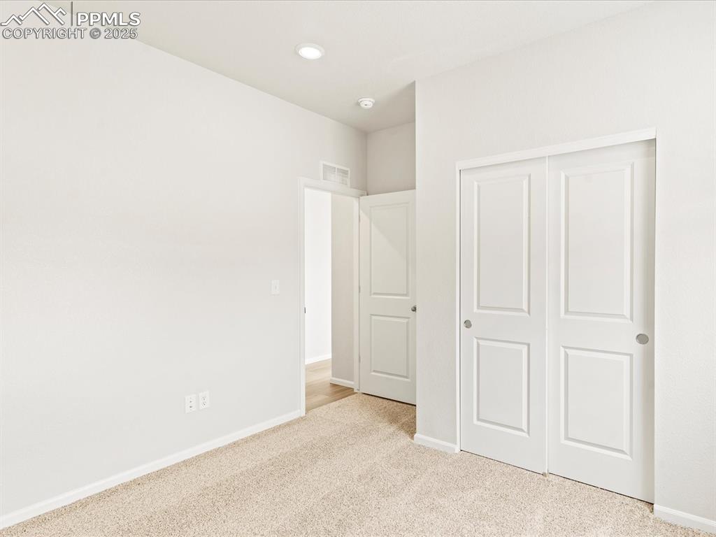 Image 12 of 32: Unfurnished bedroom with light carpet, a closet, and recessed lighting