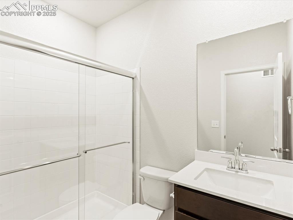 Image 13 of 32: Bathroom with vanity, a shower stall, and a textured wall