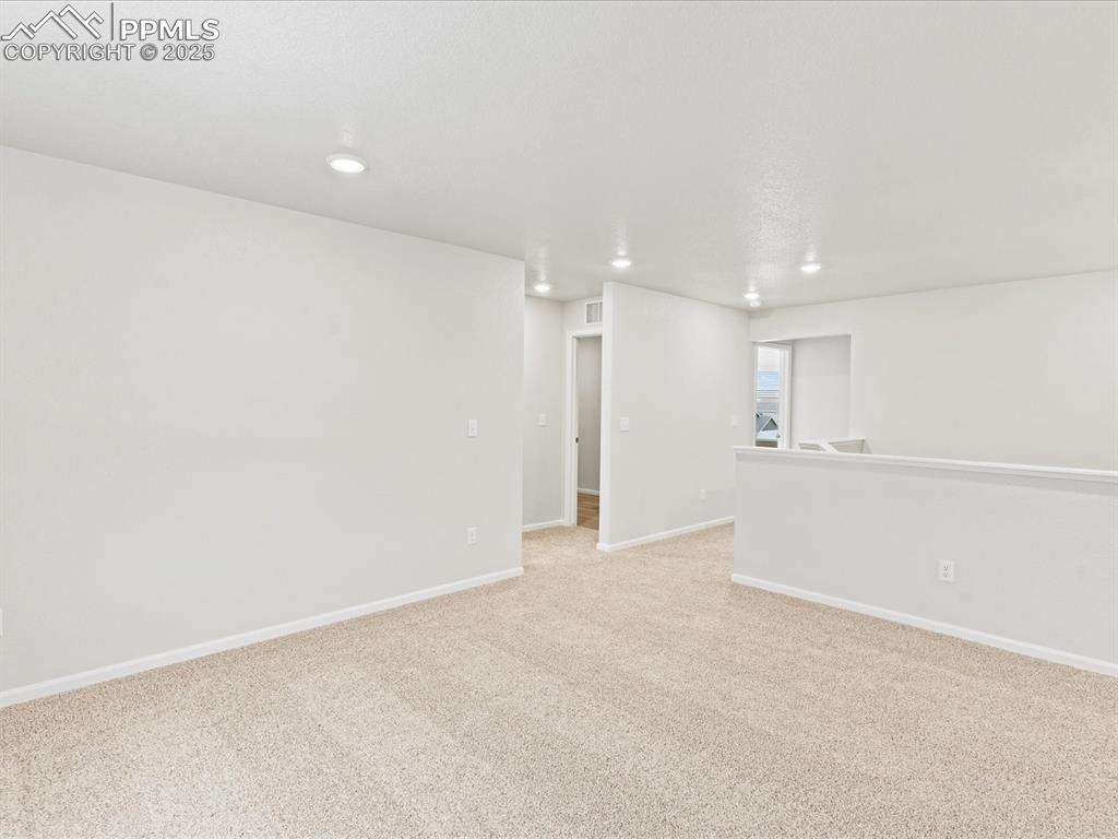 Image 14 of 32: Empty room with light colored carpet and recessed lighting