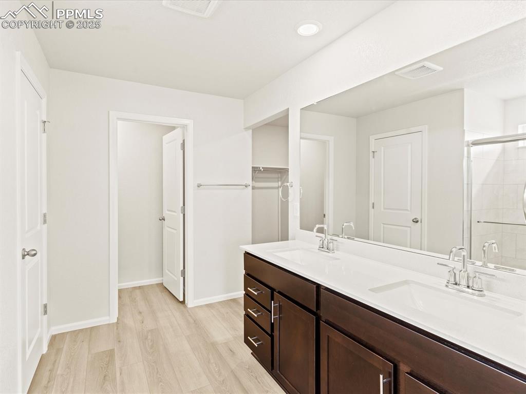 Image 16 of 32: Full bath with a shower stall, double vanity, light wood-type flooring, a s
