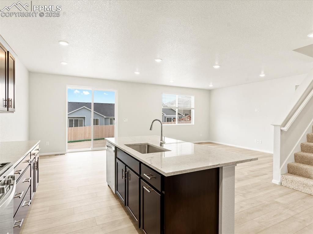 Image 6 of 32: Kitchen featuring dark brown cabinets, light wood finished floors, light st
