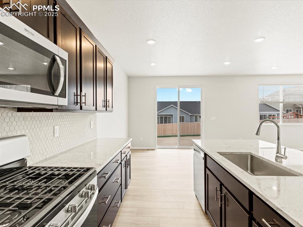 Image 7 of 32: Kitchen with dark brown cabinetry, appliances with stainless steel finishes