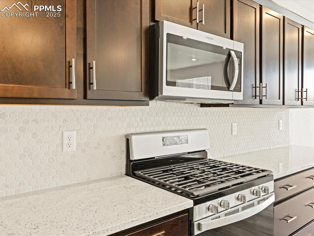 Image 8 of 32: Kitchen featuring stainless steel appliances, light stone countertops, tast