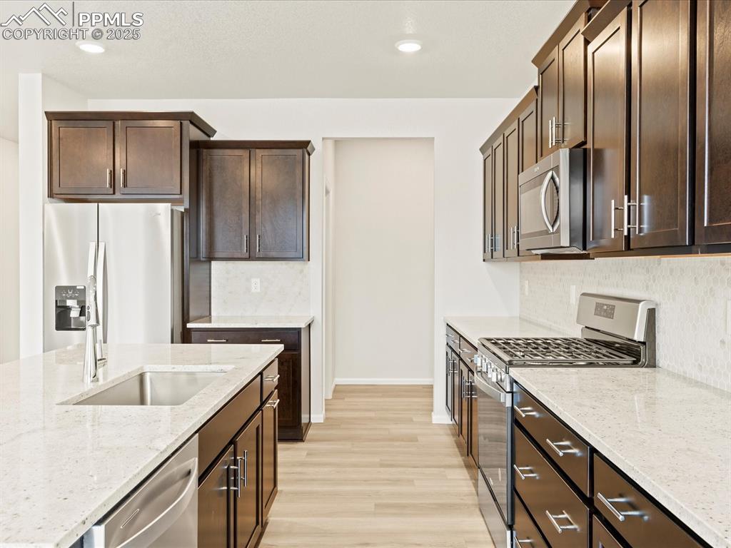 Image 9 of 32: Kitchen featuring appliances with stainless steel finishes, light stone cou
