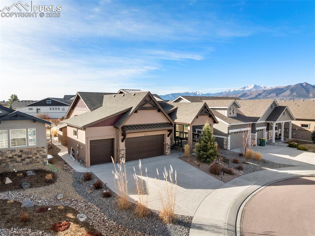 Image 1 of 49: Craftsman house with stone siding, a garage, driveway, and stucco siding