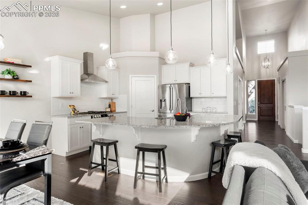 Image 15 of 49: Kitchen featuring a high ceiling, dark wood finished floors, white cabinetr