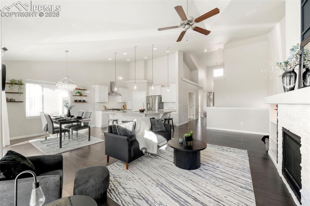 Image 16 of 49: Living area featuring a fireplace, a ceiling fan, dark wood finished floors