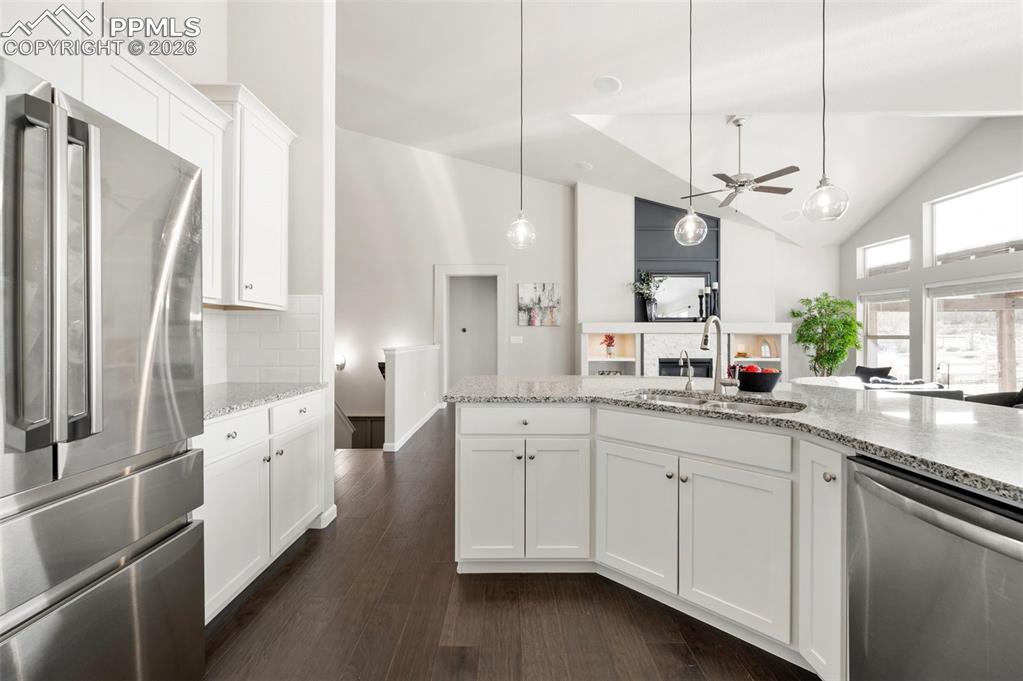 Image 17 of 49: Kitchen featuring stainless steel appliances, white cabinets, dark wood-sty