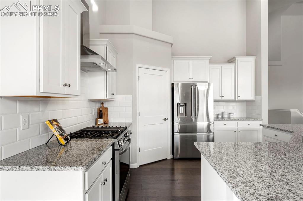 Image 18 of 49: Kitchen with light stone countertops, stainless steel appliances, white cab
