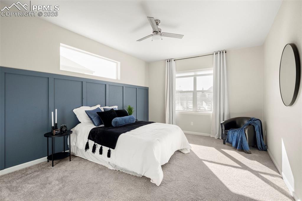 Image 23 of 49: Bedroom featuring a decorative wall, a ceiling fan, and light colored carpe