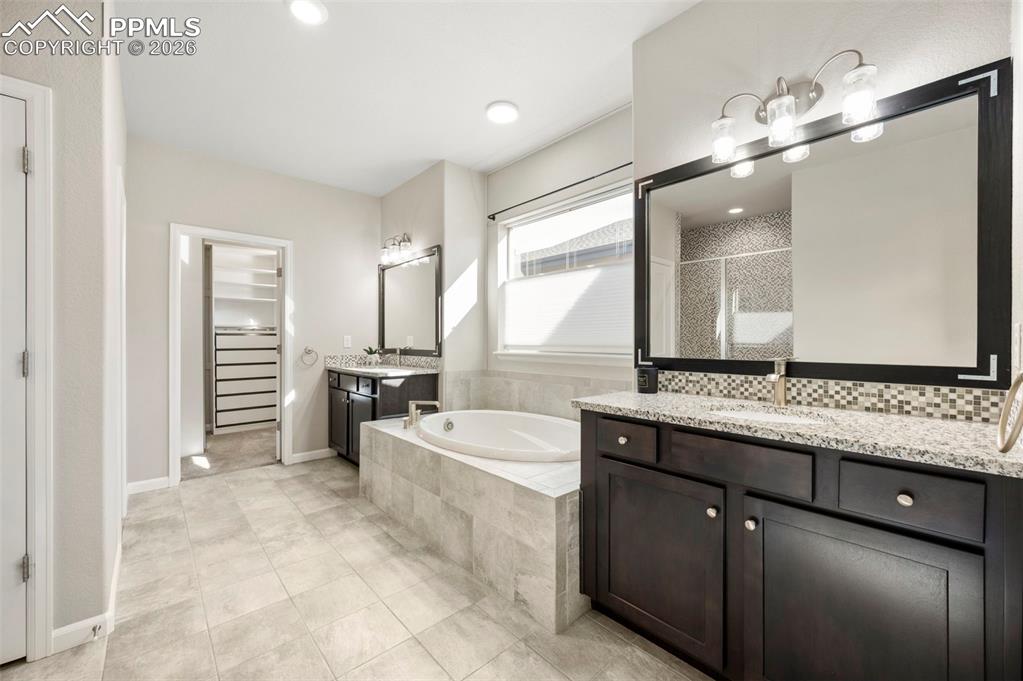 Image 26 of 49: Bathroom featuring a spacious closet, a garden tub, two vanities, a shower 