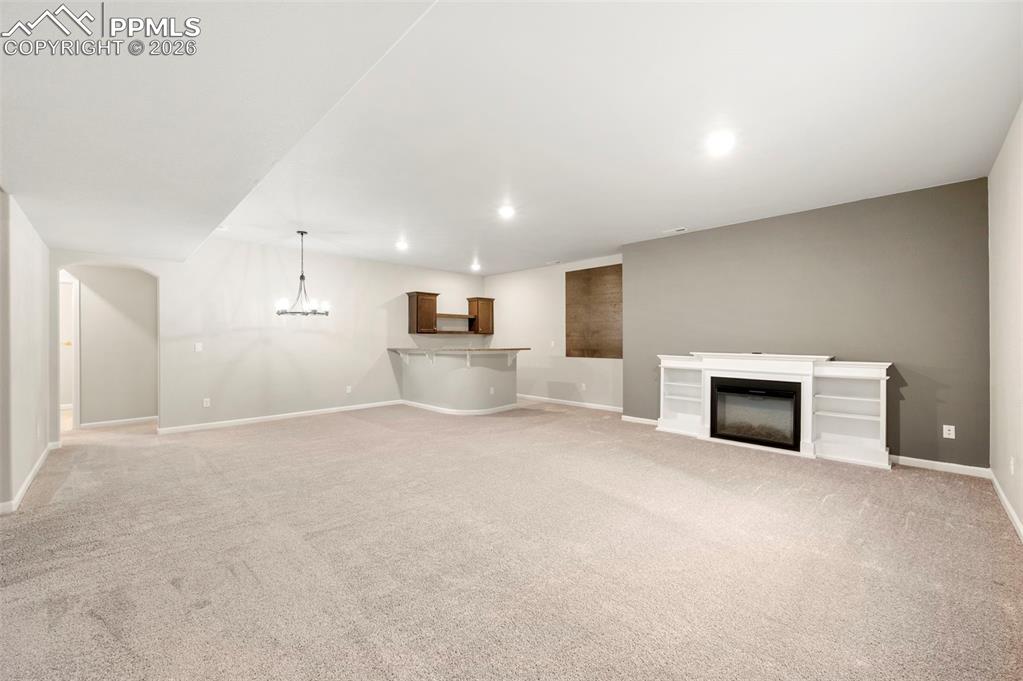 Image 32 of 49: Unfurnished living room featuring light colored carpet, a glass covered fir