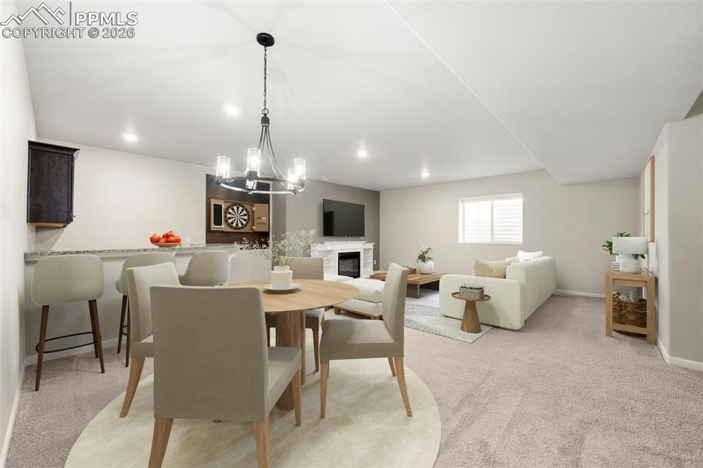 Image 33 of 49: Dining room featuring light carpet, a glass covered fireplace, and hanging 