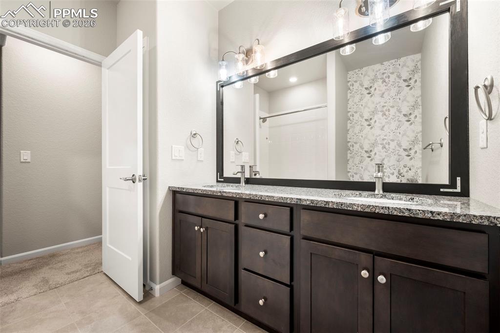Image 36 of 49: Full bath with double vanity and light tile patterned floors