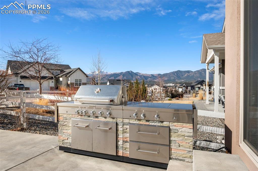 Image 38 of 49: View of patio with area for grilling, a residential view, and a mountain vi