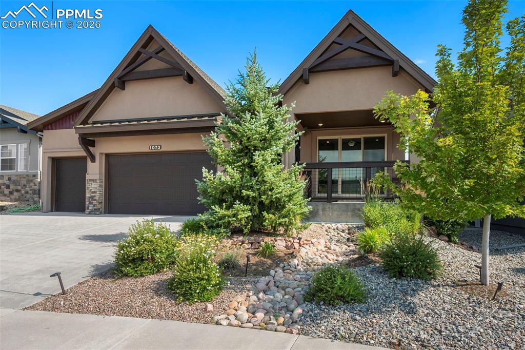 Image 6 of 49: Craftsman inspired home with stucco siding, a garage, driveway, and stone s