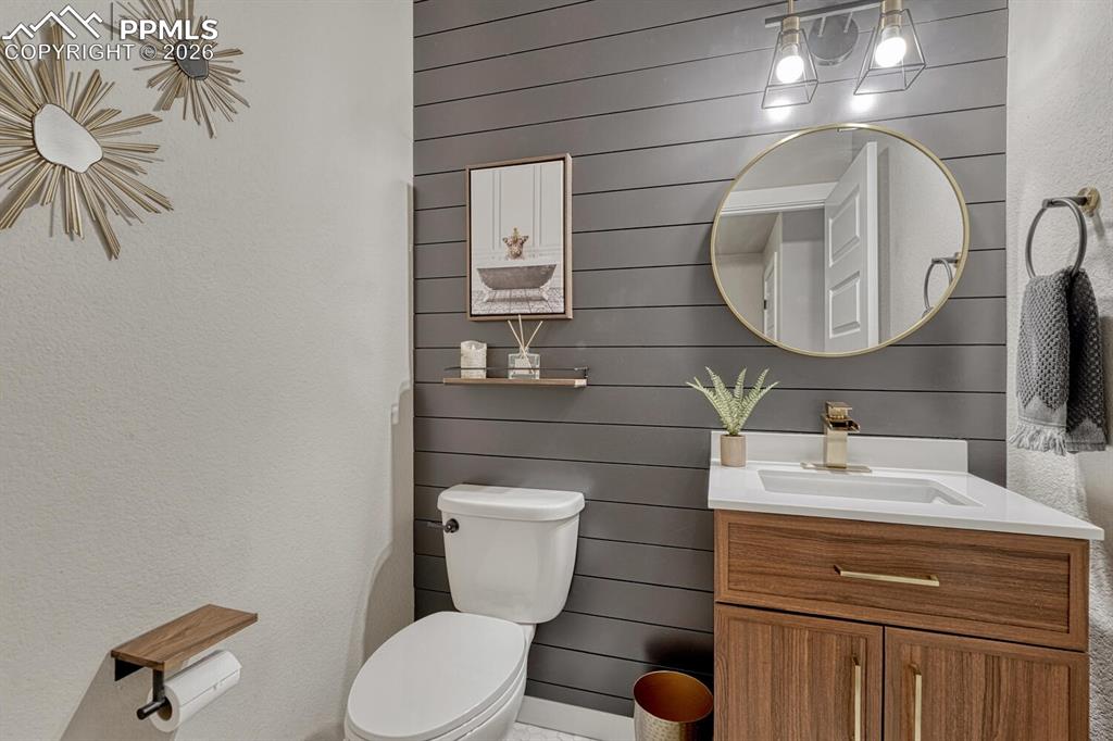Image 18 of 50: Convenient main level Powder Bathroom with vanity, round mirror, and attrac