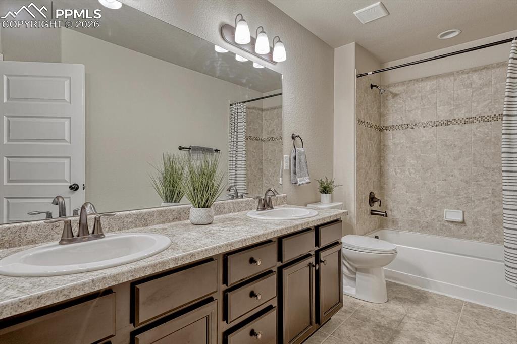 Image 23 of 50: Upper Level Full Bathroom with dual sink vanity, mirror, and tiled tub/show