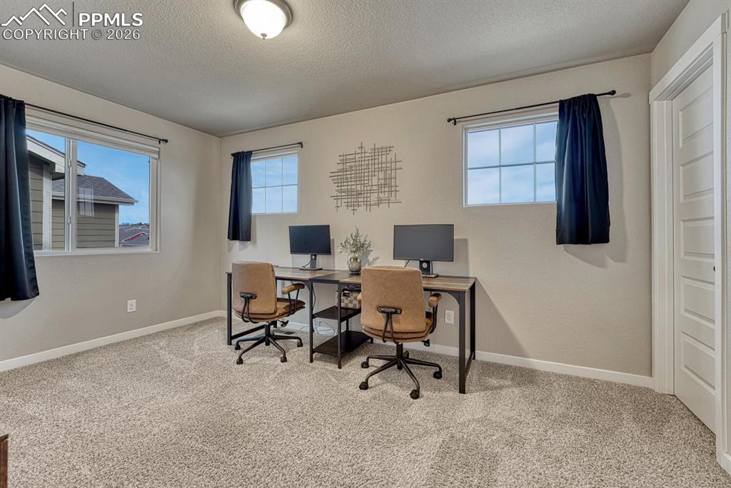 Image 26 of 50: Upper Level Bedroom #2 has neutral carpet and windows that provide lots of