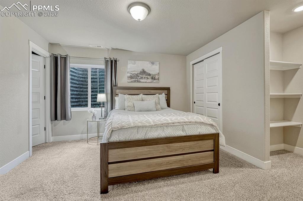Image 40 of 50: Basement Bedroom with neutral carpet, built-in shelves, and adjoining Full
