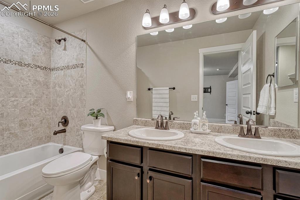 Image 43 of 50: Basement Full Bathroom with dual sink vanity, mirror, and tiled tub/shower.