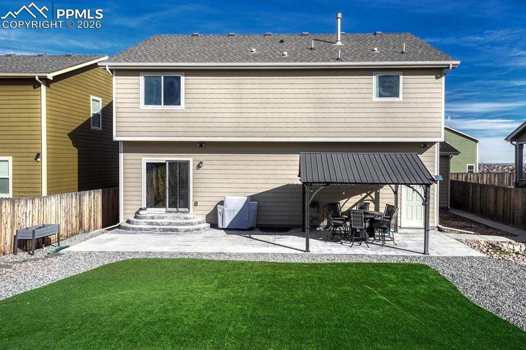 Image 47 of 50: Low maintenance, fenced backyard with expanded patio and gazebo for outdoor
