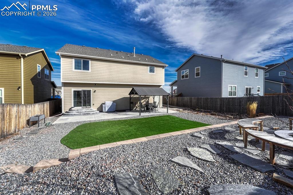Image 48 of 50: Fenced backyard with rock gardens and grass area for the kids and pets to p