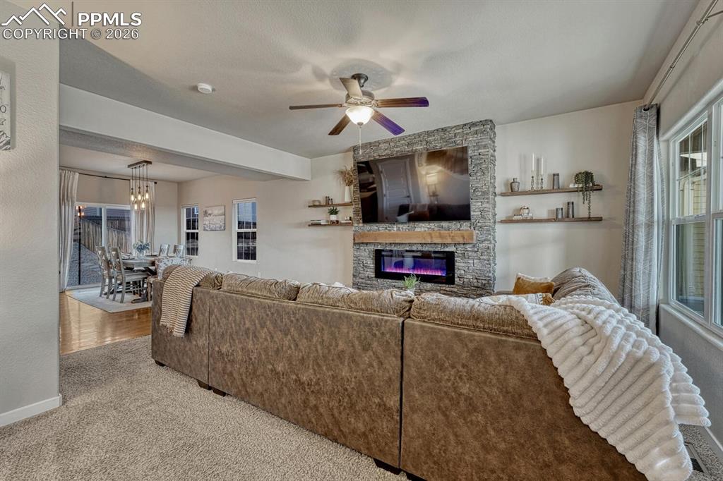 Image 7 of 50: The Living Room features neutral carpet, a lighted ceiling fan, and electri