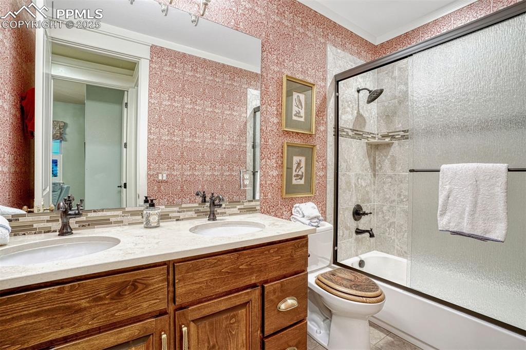 Image 26 of 45: Shared full bath with double sinks and ample storage, perfect for a busy ho