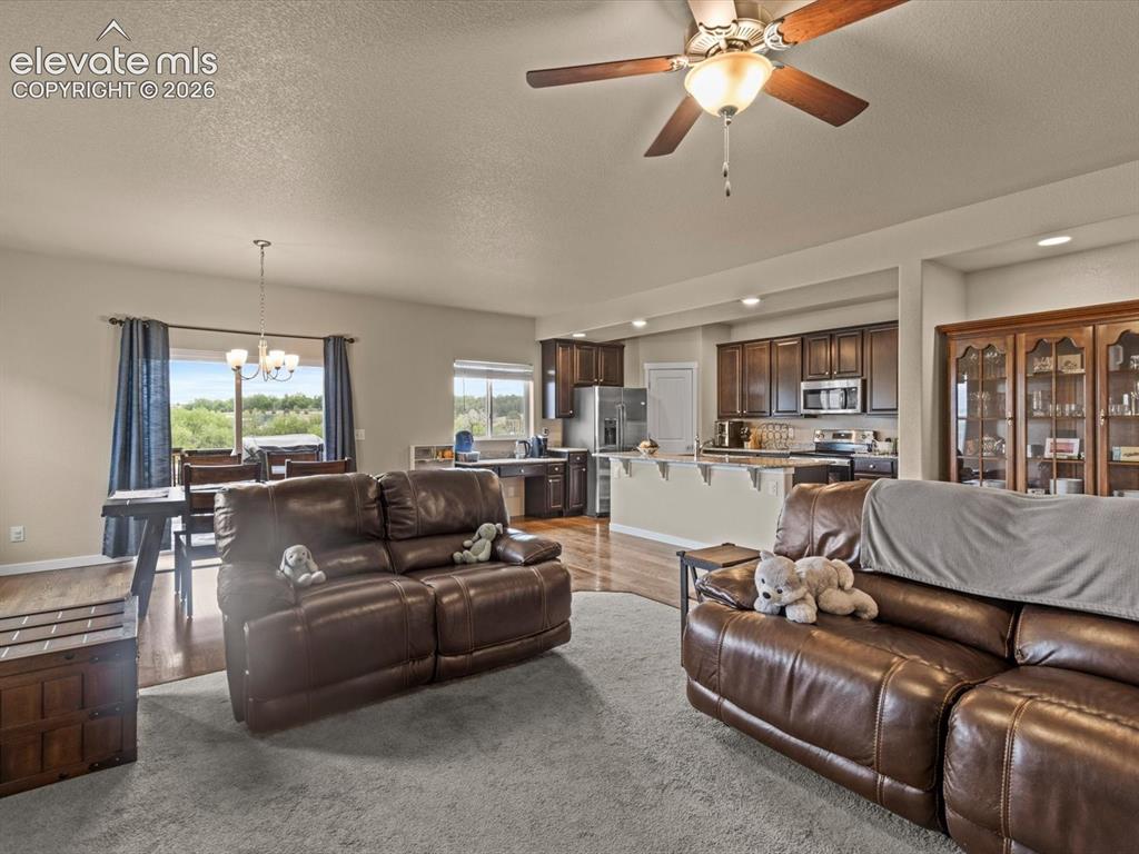 Image 10 of 45: Open-concept living area featuring a ceiling fan, carpeted flooring, and re