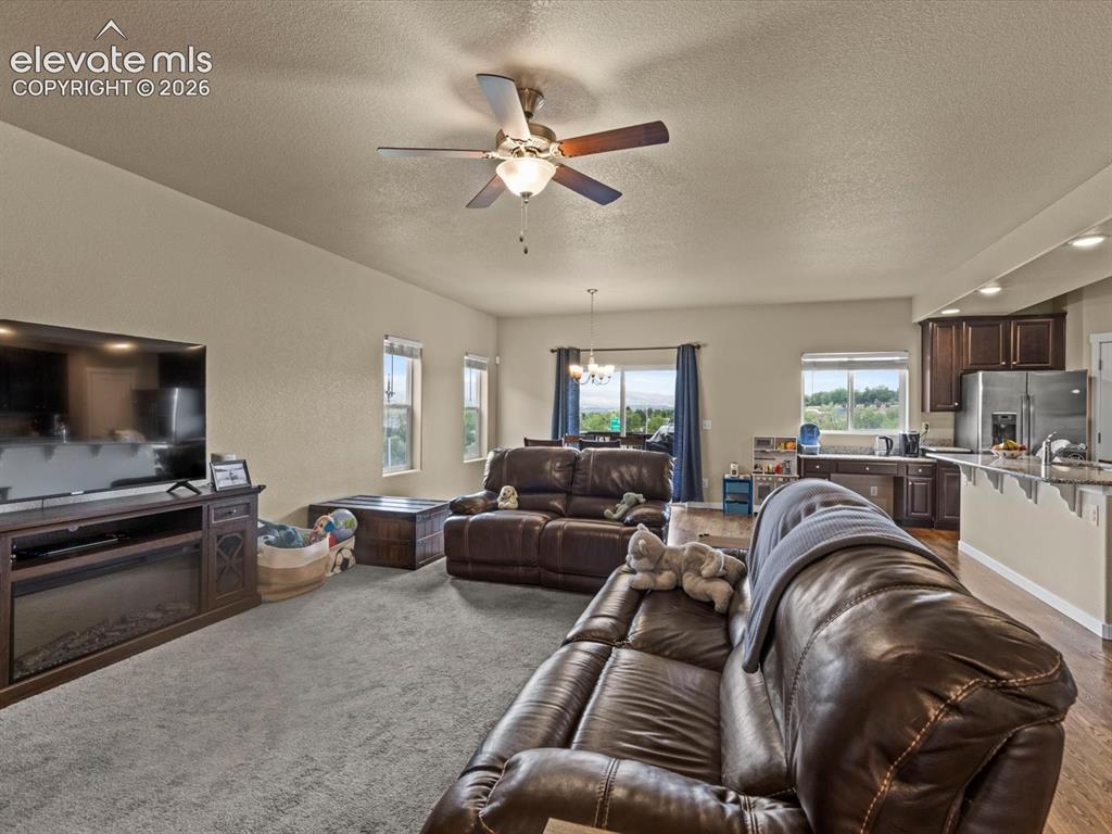Image 11 of 45: Open-concept living space featuring carpeted flooring, a ceiling fan, and m
