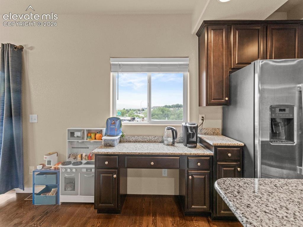 Image 16 of 45: Kitchen featuring dark wood cabinetry, light speckled countertops, stainles