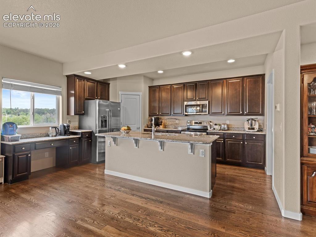 Image 17 of 45: Spacious kitchen featuring dark wood cabinetry, stainless steel appliances,