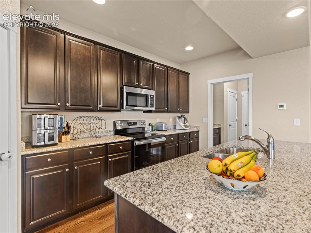 Image 18 of 45: Kitchen featuring extensive dark wood cabinetry, granite countertops, and s