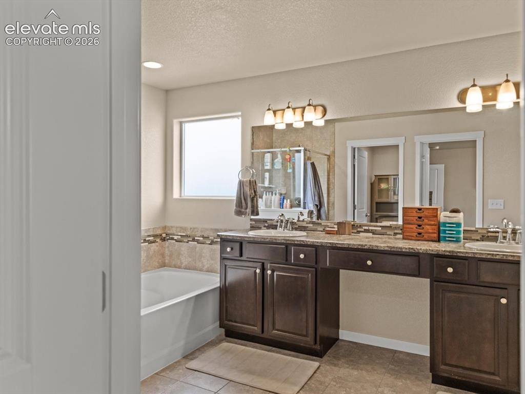 Image 31 of 45: Dual vanity with rich wood-finish cabinetry, integrated sinks, and polished
