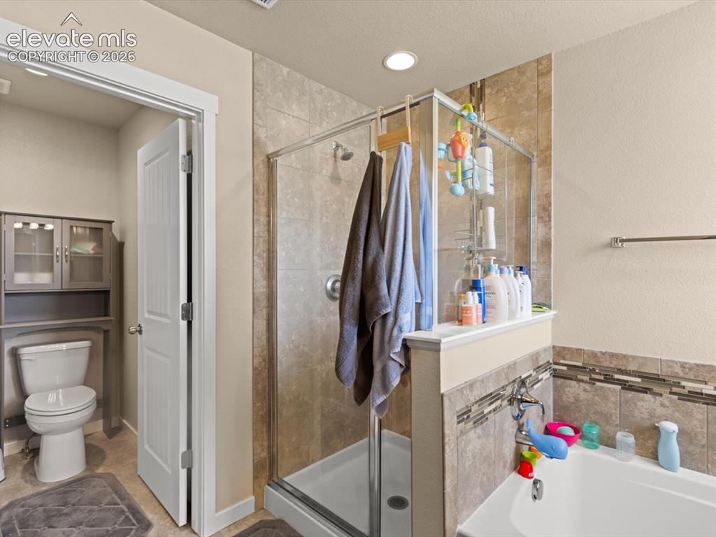 Image 32 of 45: Spacious bathroom featuring a glass-enclosed shower, built-in bathtub, and 