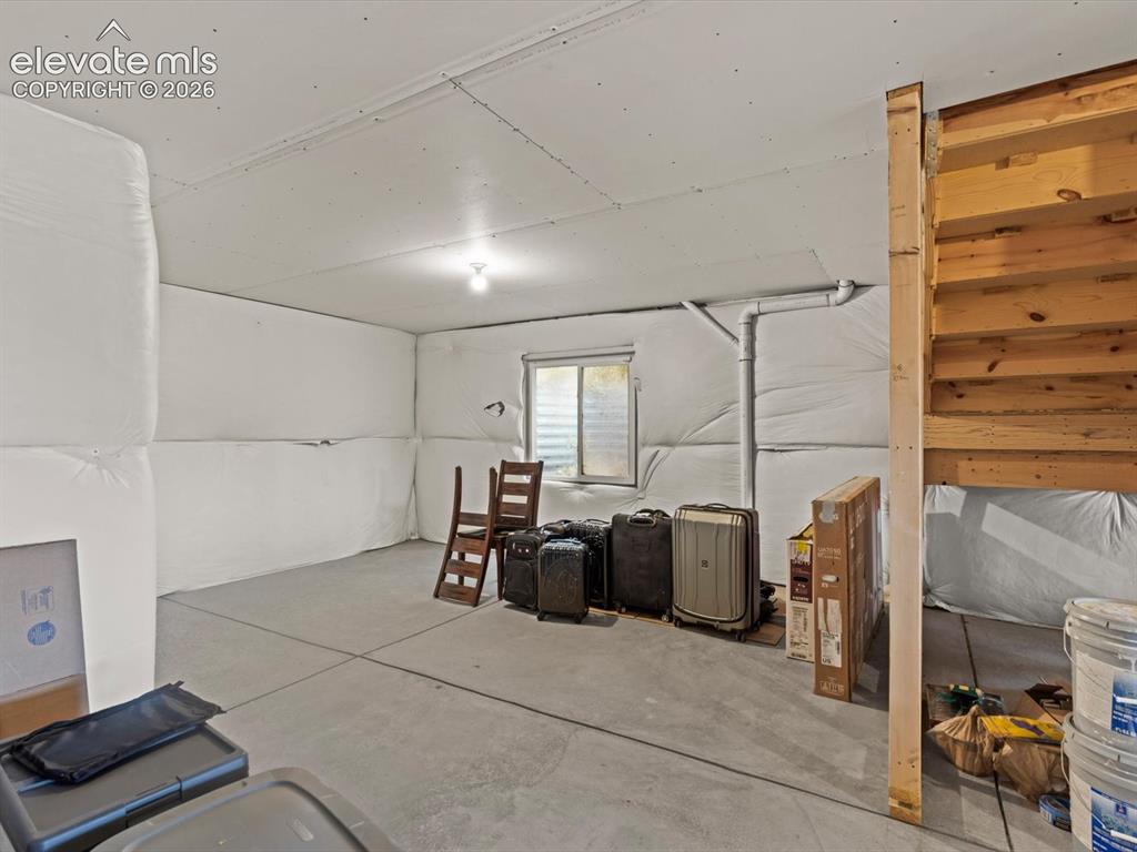 Image 39 of 45: Unfinished basement with concrete flooring, exposed ceiling joists, and a p