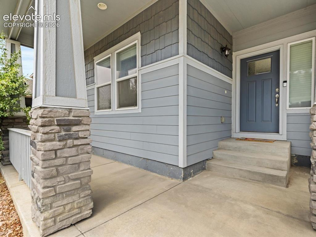 Image 4 of 45: Inviting covered front porch with stone-wrapped columns