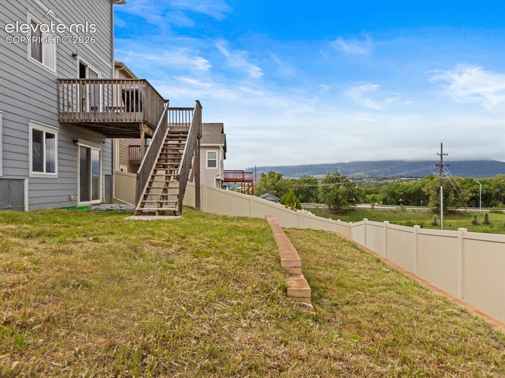 Image 43 of 45: Rear exterior featuring gray siding, an elevated wood deck with stairs, and
