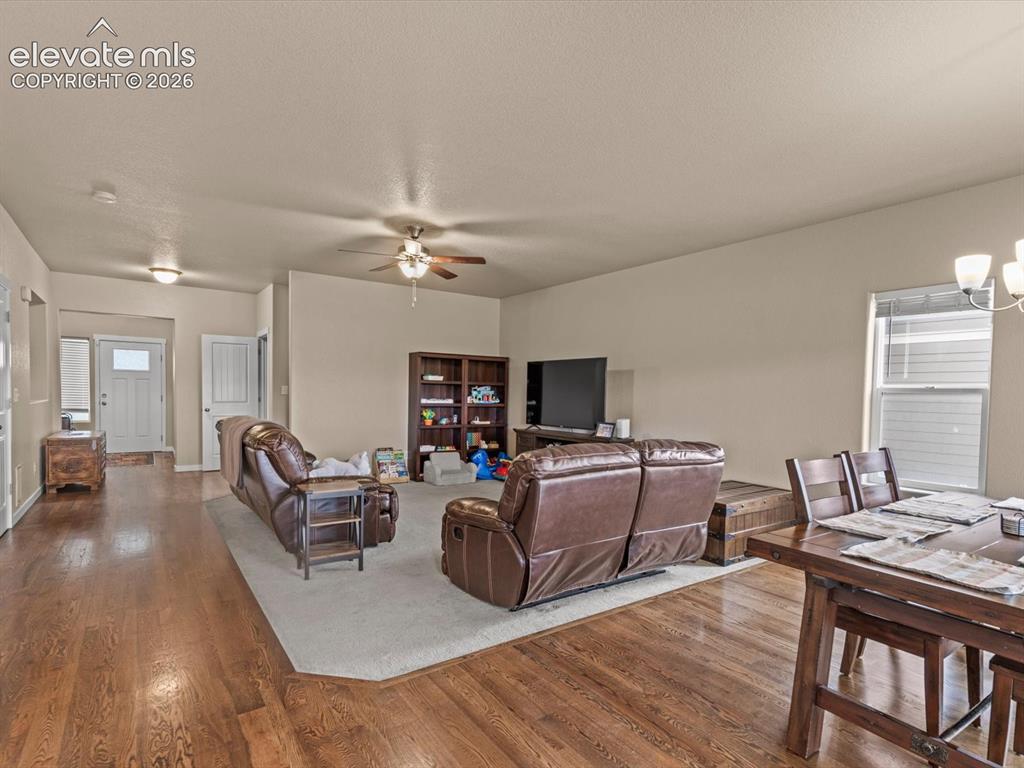 Image 8 of 45: Open-concept living area featuring wood-finish flooring, a ceiling fan, and