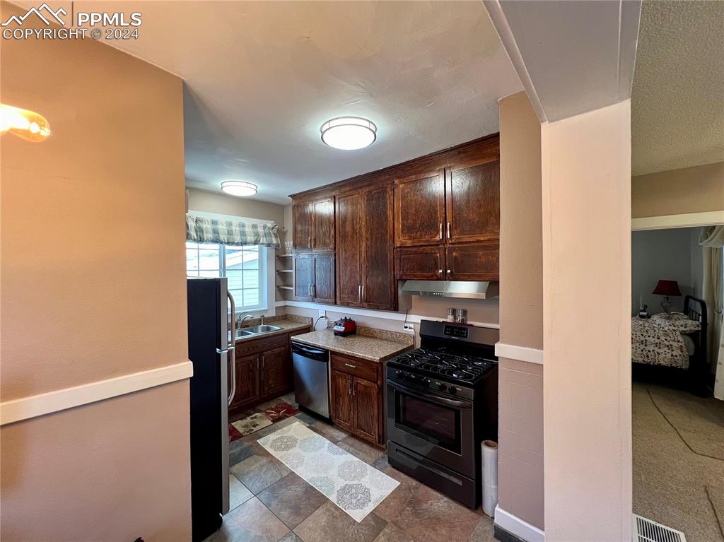Image 15 of 18: Kitchen with sink, appliances with stainless steel finishes, dark brown cab
