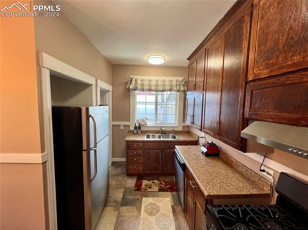 Image 16 of 18: Kitchen with appliances with stainless steel finishes, sink, light stone co