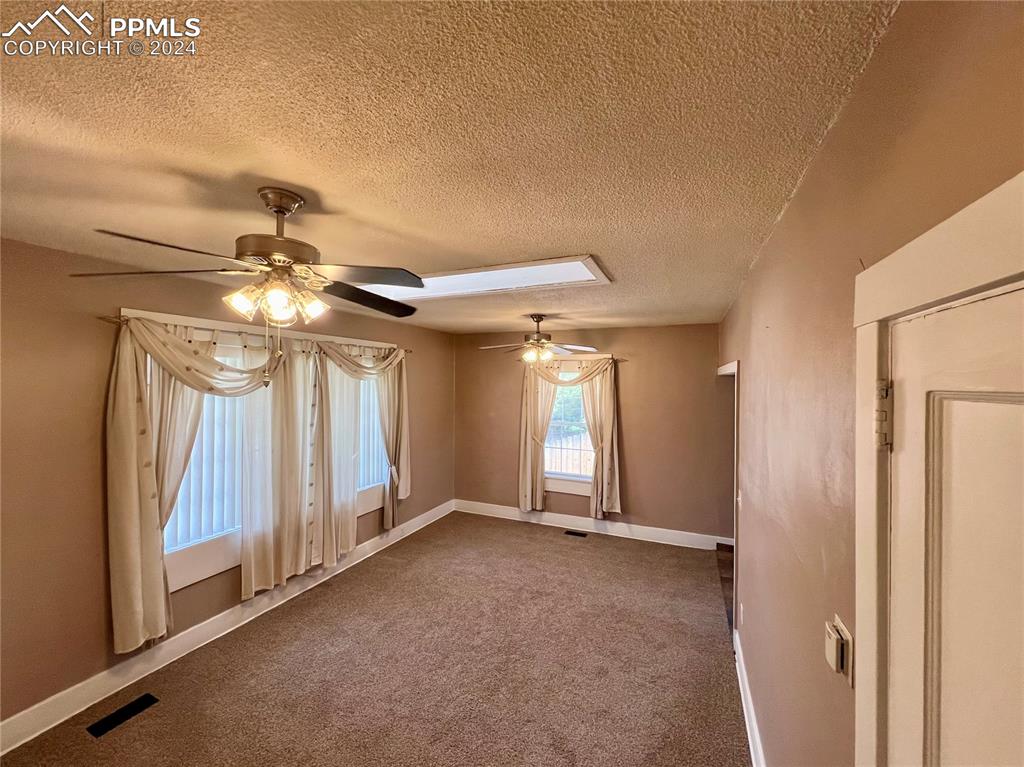 Image 7 of 18: Carpeted empty room with ceiling fan and a textured ceiling