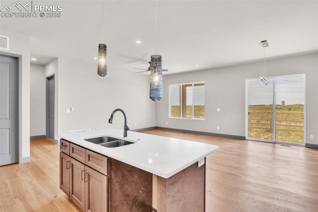 Image 15 of 50: Kitchen featuring hanging light fixtures, light countertops, light wood-sty