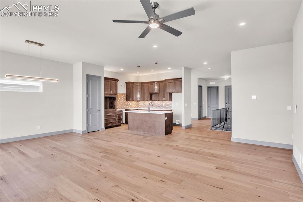 Image 19 of 50: Kitchen with light wood finished floors, tasteful backsplash, open floor pl