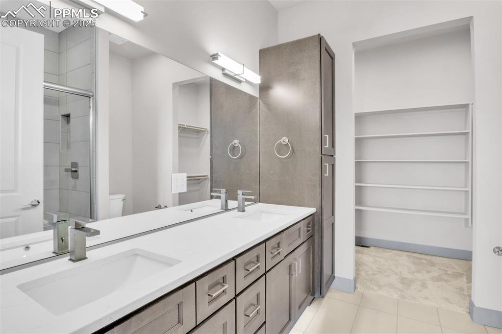 Image 22 of 50: Full bathroom featuring a sink, a shower stall, a spacious closet, and tile